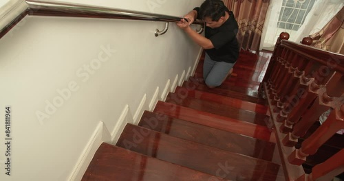 Asian man slowly going up staircase by crawl on knees at home, Holding handrail. Safety first at home concept.