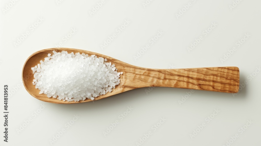 Wooden spoon filled with coarse sea salt resting on white background Wooden spoon filled with coarse sea salt resting on white background