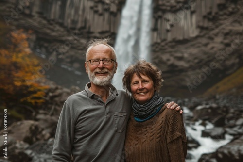 Portrait of a grinning caucasian couple in their 30s showing off a thermal merino wool top in front of backdrop of a spectacular waterfall © Markus Schröder