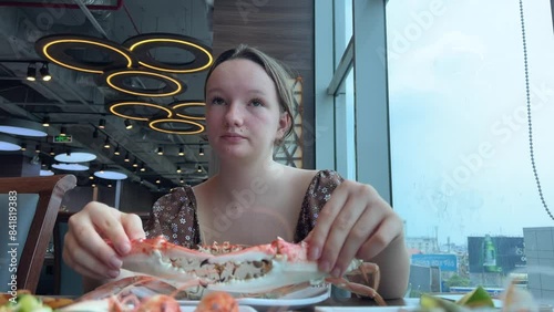 The girl takes the cancer out of the boiling water and puts it on a plate with the others. Girl eating big snow crab in a restaurant photo