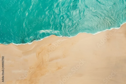 Turquoise ocean water gently crashes on golden sandy beach, creating foam under sunny summer sky © Enigma