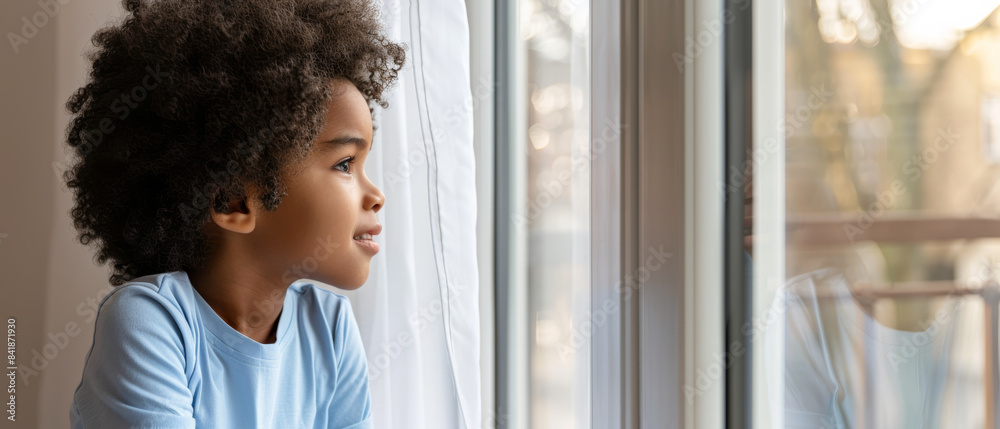 A young child with curly hair gazes out of a window, illuminated by natural light, reflecting a sense of wonder and anticipation. A young child with curly hair gazes out of a window, illuminated by natural light, reflecting a sense of wonder and anticipation.