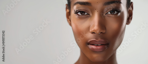 A close-up portrait of a woman with a serene expression, showcasing her natural beauty with minimal makeup under soft, diffused lighting.