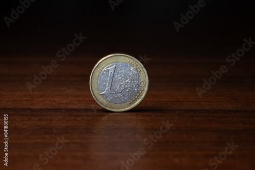 a one euro coin stands on a wooden table