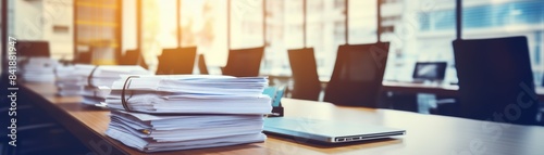 A stack of books is on a table next to a laptop. The books are piled high and the laptop is open. The scene suggests that someone is working or studying, possibly for a long period of time © Media Srock