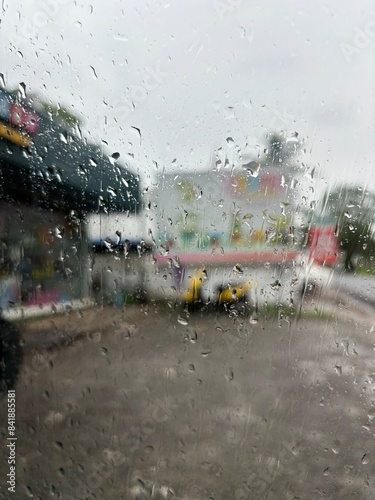 A captivating photo of raindrops on a car window, taken from inside the vehicle. This image beautifully captures the serene and reflective mood created by rain, with droplets distorting the view outsi photo