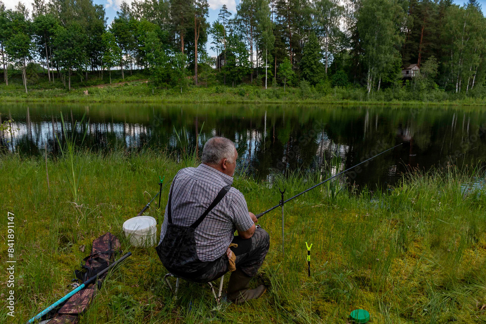 fisherman on the shore of a quiet, small lake, beautiful summer day fisherman on the shore of a quiet, small lake, beautiful summer day