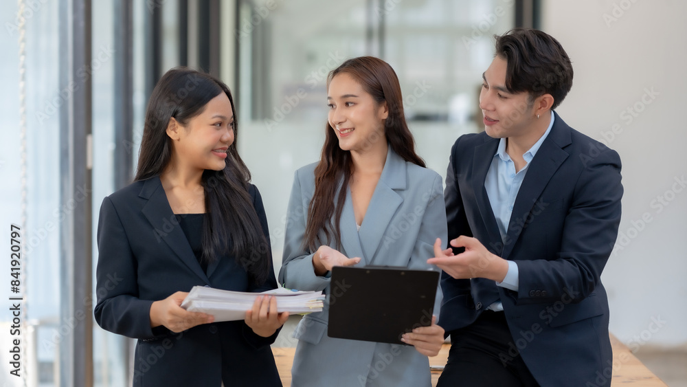 Three business professionals in a modern office discussing documents and collaborating on a project while smiling and sharing ideas. Three business professionals in a modern office discussing documents and collaborating on a project while smiling and sharing ideas.