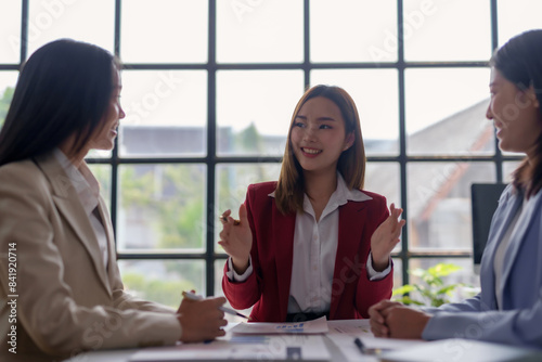 Professional business meeting with three confident women discussing ideas in a modern office setting.