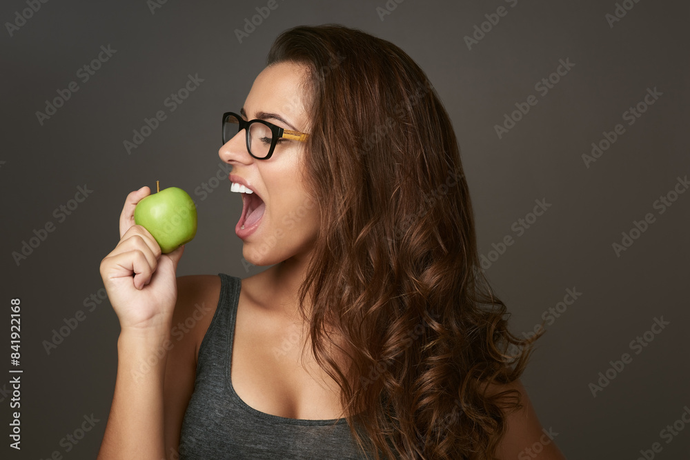 Studio background, bite and apple with woman for eating, vitamin c and mineral for nutrition. Female nutritionist, organic fruit and healthy diet for detox, weight loss or product benefits with pride Studio background, bite and apple with woman for eating, vitamin c and mineral for nutrition. Female nutritionist, organic fruit and healthy diet for detox, weight loss or product benefits with pride