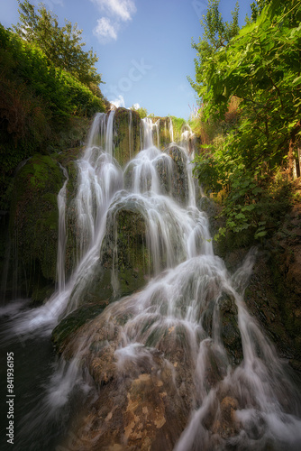 Vertical view of one of the waterfalls in Tobera, Burgos with the morning sun hitting part of it