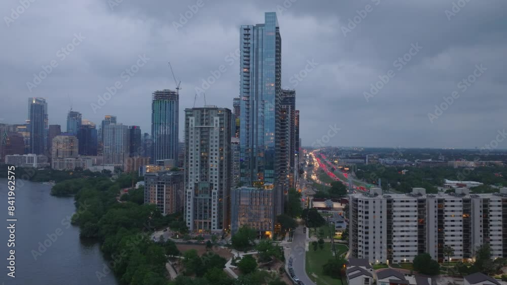 Aerial view of Austin's skyline at dusk, featuring tall buildings along lady bird lake with glowing streets and a cloudy sky Aerial view of Austin's skyline at dusk, featuring tall buildings along lady bird lake with glowing streets and a cloudy sky