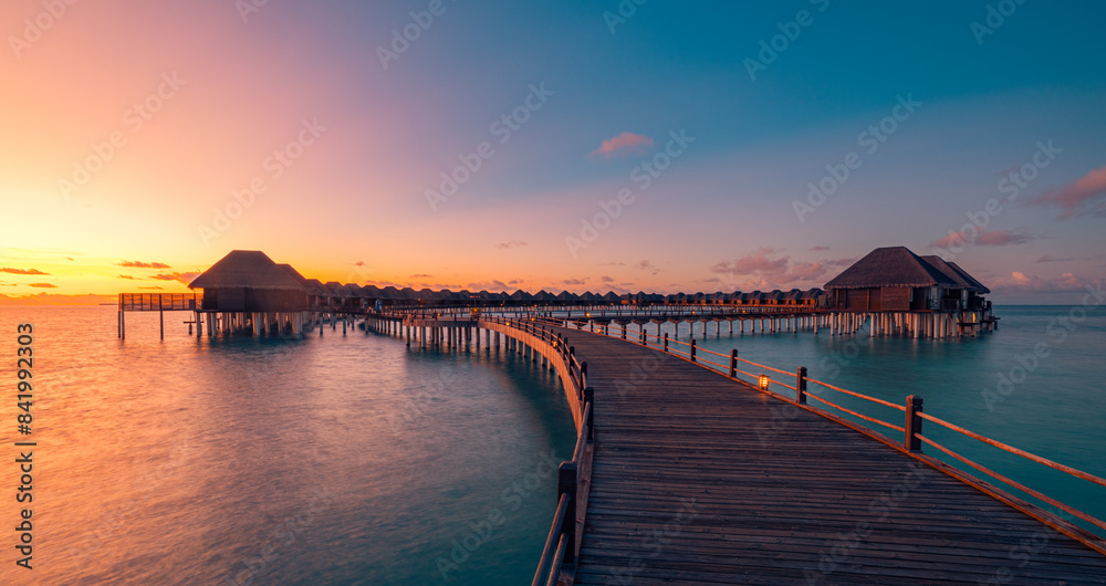 Amazing travel beach luxury landscape. Beautiful Maldives tourism sunset seascape view. Horizon colorful sea sky, over water villa pier pathway led lights. Tranquil island, vacation travel background Amazing travel beach luxury landscape. Beautiful Maldives tourism sunset seascape view. Horizon colorful sea sky, over water villa pier pathway led lights. Tranquil island, vacation travel background