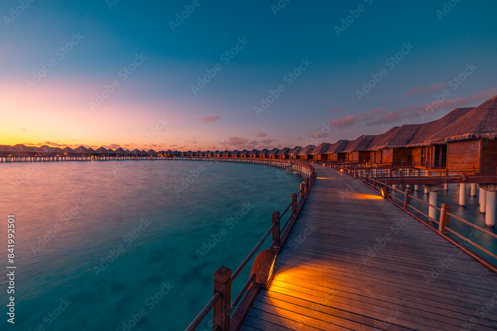 Obraz premium Amazing travel beach luxury landscape. Beautiful Maldives tourism sunset seascape view. Horizon colorful sea sky, over water villa pier pathway led lights. Tranquil island, vacation travel background