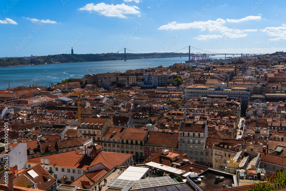 Fototapeta premium Suspension bridge Ponte 25 de Abril in Lisbon, Portugal. View of colourful facades and The 25th April Bridge over river Tagus (Tejo).