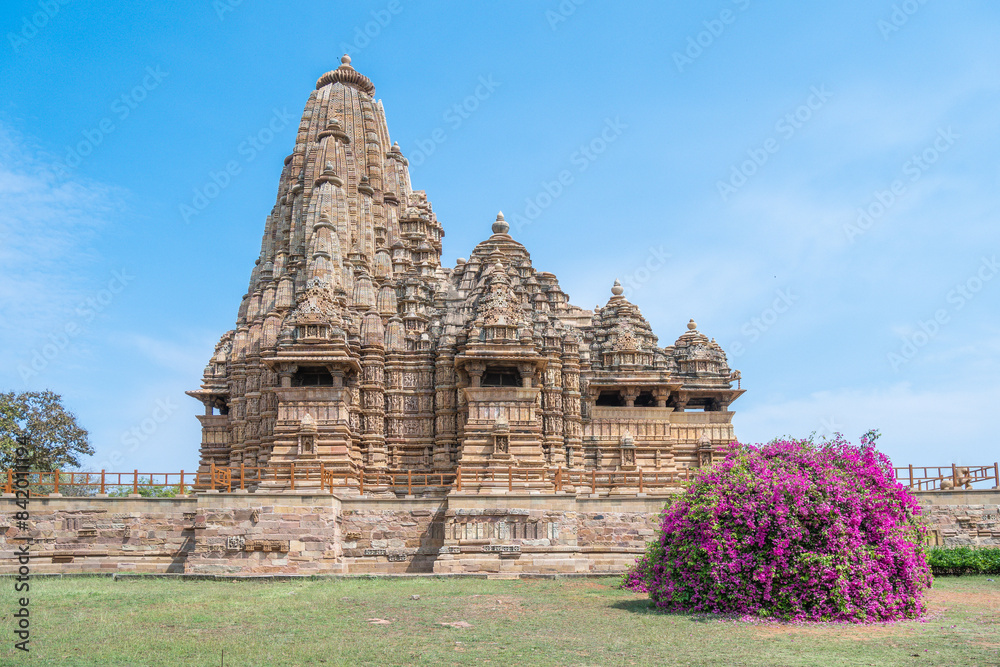 Ancient Indian Khajuraho temple of structure featuring intricate carvings and vibrant floral foreground