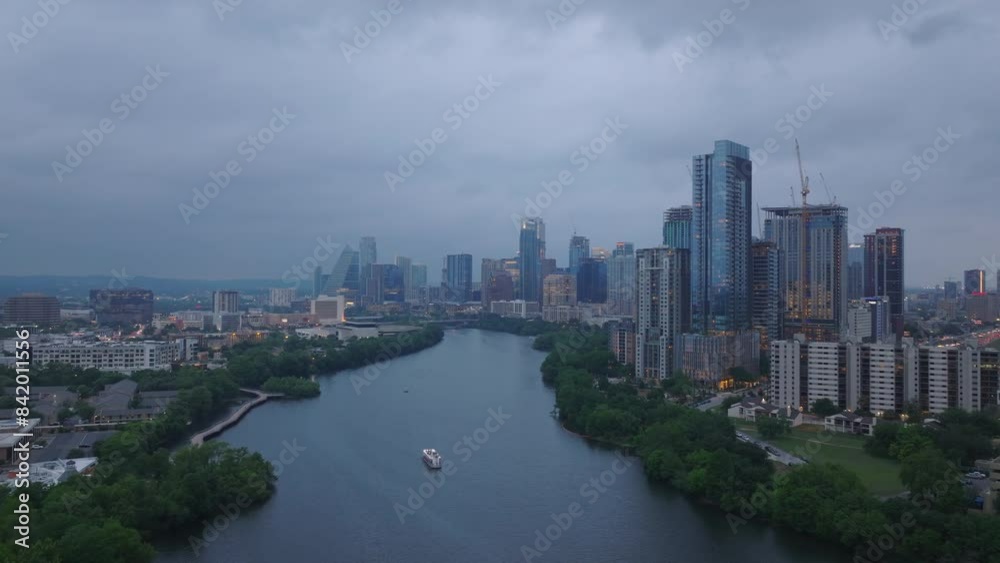 Aerial view of Austin, Texas at dusk, featuring downtown skyline, high rise buildings, and scenic river with a boat. Cityscape and travel concepts Aerial view of Austin, Texas at dusk, featuring downtown skyline, high rise buildings, and scenic river with a boat. Cityscape and travel concepts
