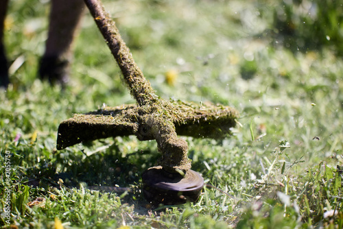 фотографія Casing and rod of working gasoline line trimmer are covered with chopped grass, close-up