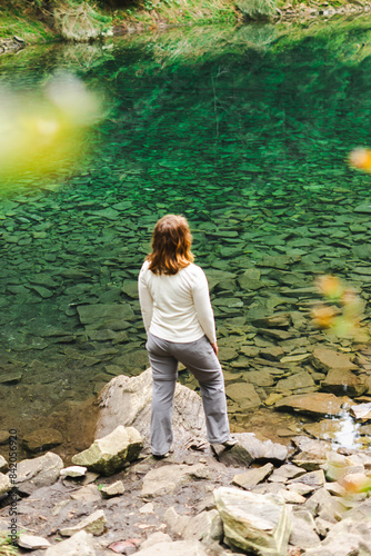 a woman looks at a lake in the forest in the middle of the mountains background, blue clear water, Rosokhan in the Carpathians, the Arshytsia ridge, spring, tourism, trekking, hiking, nature, dream photo