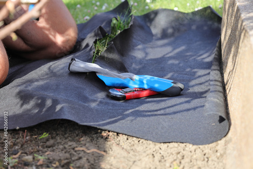 Laying an anti-weed mat in the garden together with paving stones and decorative pebbles