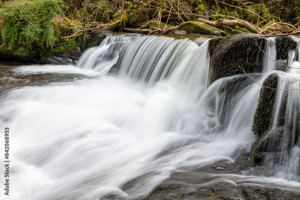 Long exposure of a waterfall flowing through the woods at Watersmeet in Exmoor National Park