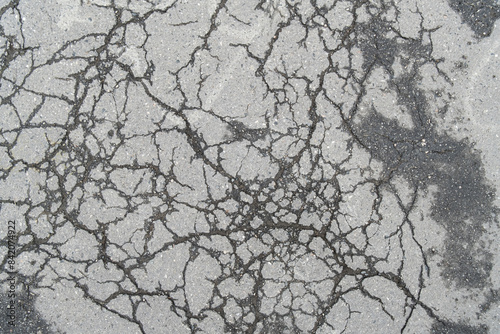 damaged surface of old, cracked asphalt shows the condition of the road with visible cracks.