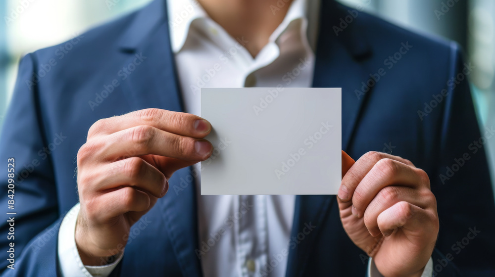 Fototapeta premium Businessman in suit holding blank card with both hands, close-up. Corporate identity and networking concept