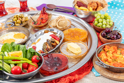 Traditional Turkish Breakfast Table (Serpme Kahvalti). Traditional Turkish village breakfast with fried eggs in a copper pan, menemen, honey clotted cream, cheese varieties on a wooden table.