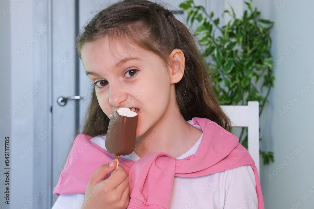 Happy smiling girl eating ice cream at home in living room. Children eat sweet food during holidays. Children's leisure concept. Selective focus. Happy smiling girl eating ice cream at home in living room. Children eat sweet food during holidays. Children's leisure concept. Selective focus.