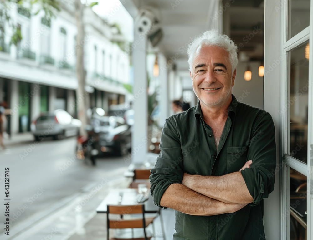 Obraz premium A smiling middle-aged man with gray hair, standing at a cafe entrance
