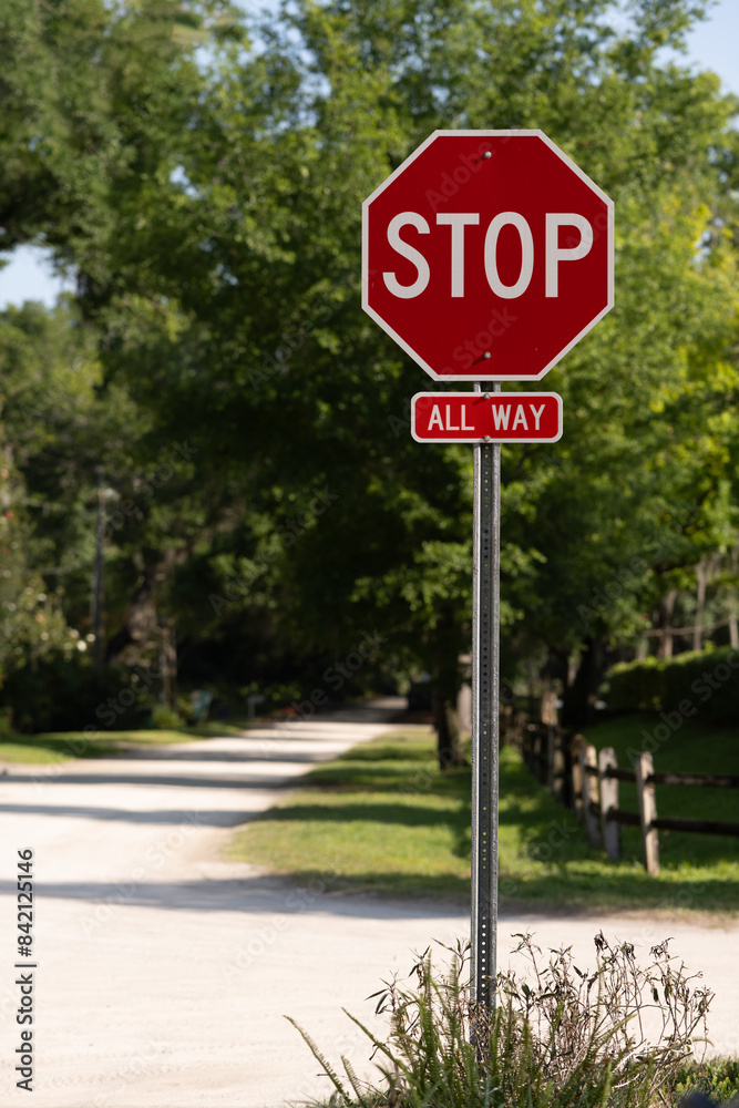 STOP sign in full sun with path and fence behind, empty left side for copy space STOP sign in full sun with path and fence behind, empty left side for copy space