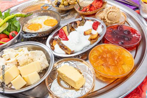 Traditional Turkish Breakfast Table (Serpme Kahvalti). Traditional Turkish village breakfast with fried eggs in a copper pan, menemen, honey clotted cream, cheese varieties on a wooden table. photo