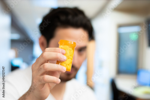 Portrait and close up of man holding bottle of pills in hospital room with copy space
