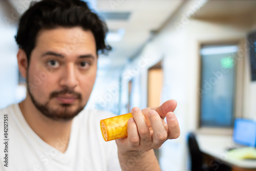 Portrait and close up of man holding bottle of pills in hospital room with copy space