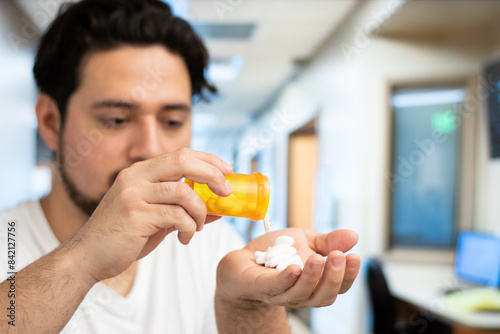 Close up of man putting many pills in his hand in a hospital room with copy space