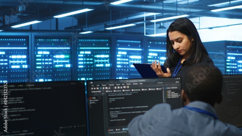 Manager overseeing server room, walking around with checklist on notepad, troubleshooting hardware. Supervisor doing inspection in server hub, monitoring energy consumption across rigs