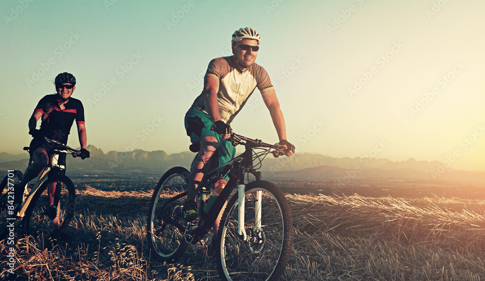 Sunset, men and friends in bicycle race with helmet, exercise and adventure trail in nature together. Cycling, fitness and people with mountain bike in evening for outdoor workout, energy and smile