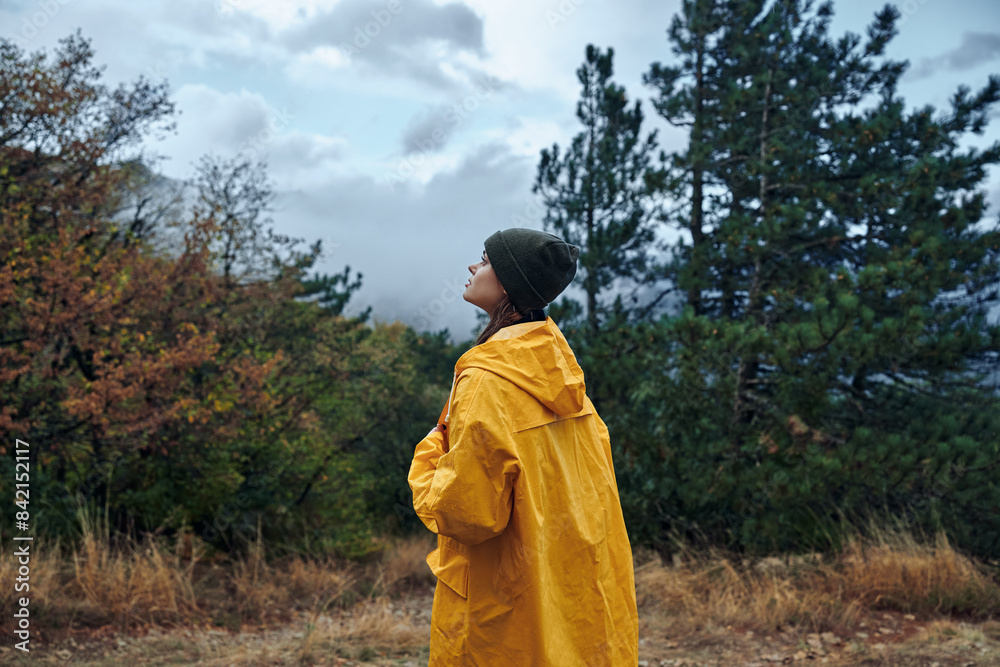 Solo traveler in a vibrant yellow raincoat standing in a vast green field admiring the sky at sunset Solo traveler in a vibrant yellow raincoat standing in a vast green field admiring the sky at sunset