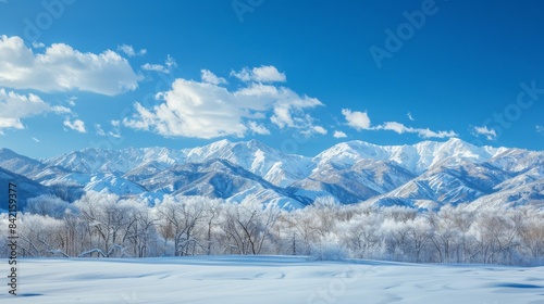 A panoramic view of a snowy mountain range under a crystal clear winter sky, reflecting the cold beauty of the season © Lakkhana