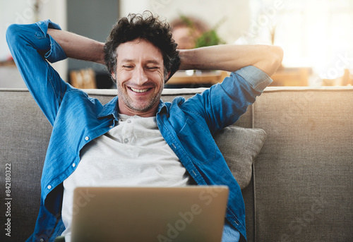 Foto Stretching, relax and happy man on laptop in home living room, wellness or smile with reading email online