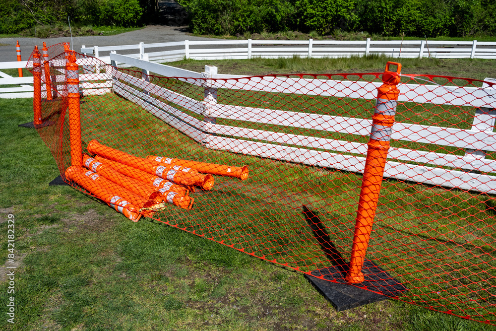 Decayed white fence surrounded by orange mesh safety fence and bollards, replacing old wood pasture fence project, sunny spring farm maintenance project
Decayed white fence surrounded by orange mesh safety fence and bollards, replacing old wood pasture fence project, sunny spring farm maintenance project