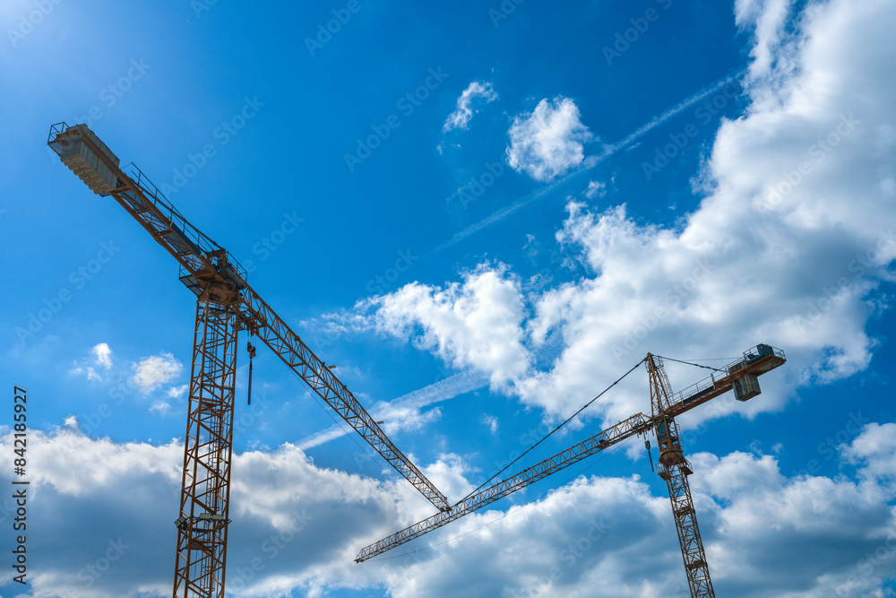 Construction cranes on a background of blue sky. Construction concept. Construction cranes on a background of blue sky. Construction concept.