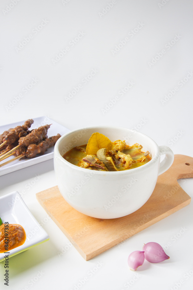 Gulai curry, indonesian traditional food on wood plate with onion, isolated background Gulai curry, indonesian traditional food on wood plate with onion, isolated background