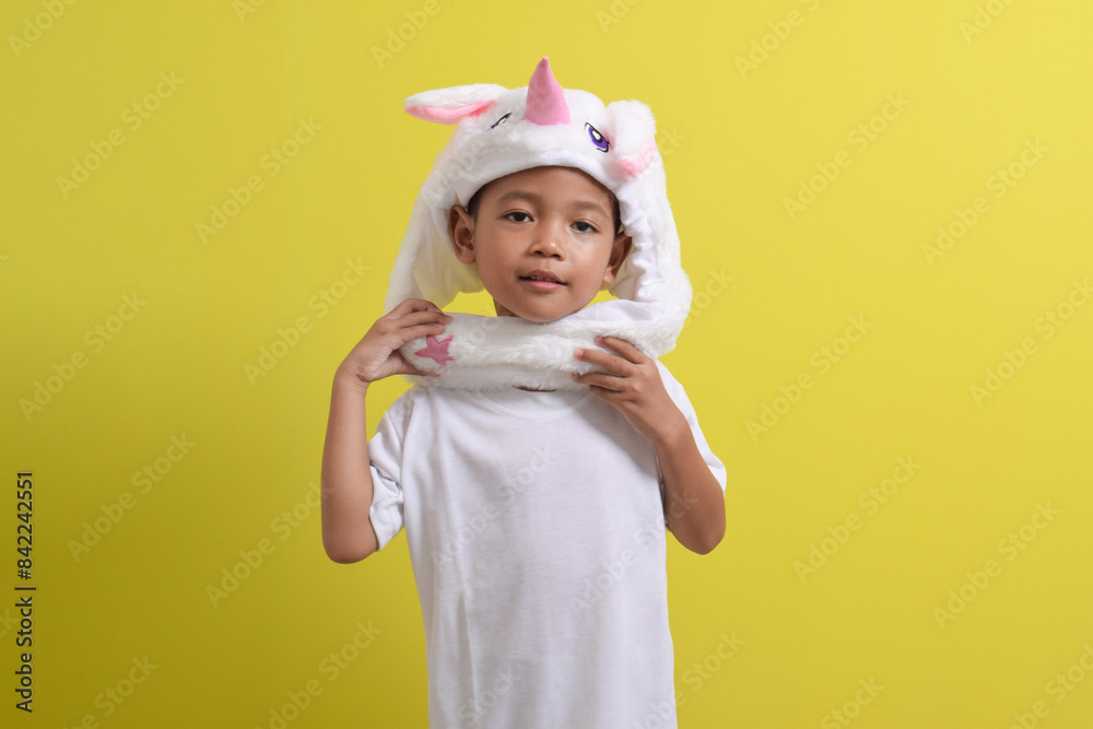 Asian little boy posing wearing cute character hat on yellow background. Portrait of a cute Asian boy Asian little boy posing wearing cute character hat on yellow background. Portrait of a cute Asian boy