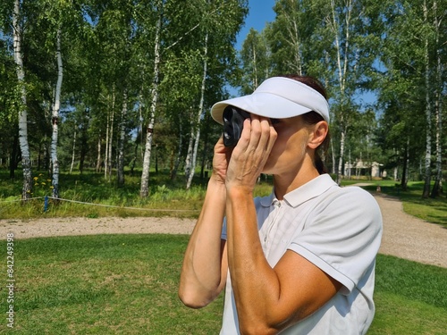 Woman Using Golf Rangefinder on Course During Summer Day