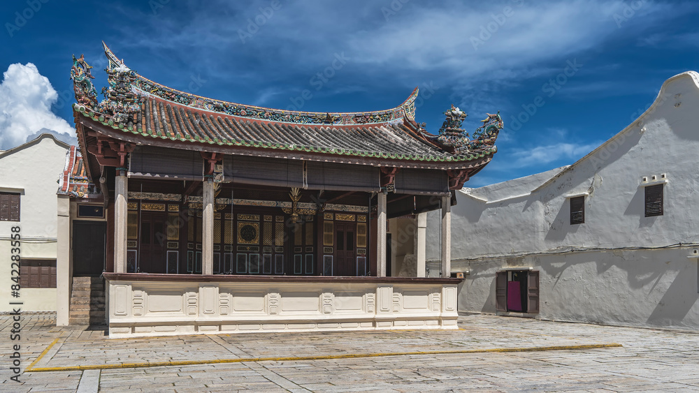 The building of an ancient Chinese-style theater. A scene with columns. The walls with golden ornaments. The roof with curved edges is decorated with figures of mythical creatures, dragons. Malaysia. The building of an ancient Chinese-style theater. A scene with columns. The walls with golden ornaments. The roof with curved edges is decorated with figures of mythical creatures, dragons. Malaysia.