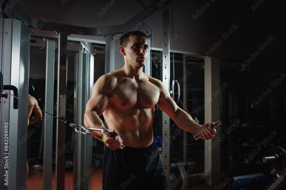 Focused sportsman working out arm muscles on the simulator in dark gym at night. the concept of a sporty lifestyle. Focused sportsman working out arm muscles on the simulator in dark gym at night. the concept of a sporty lifestyle.