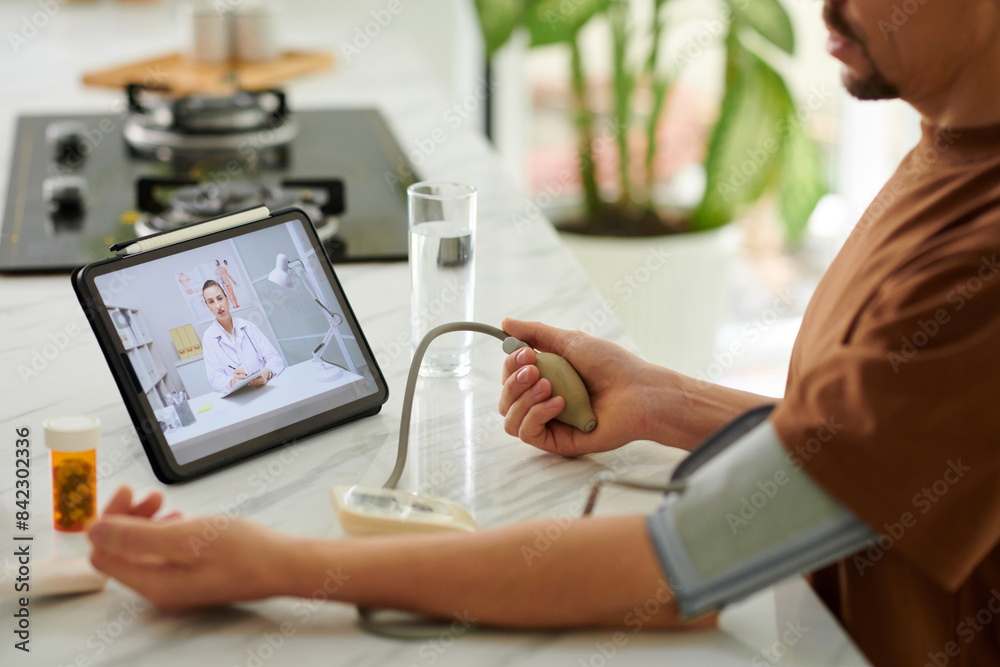 Man measuring his blood pressure under control of online doctor