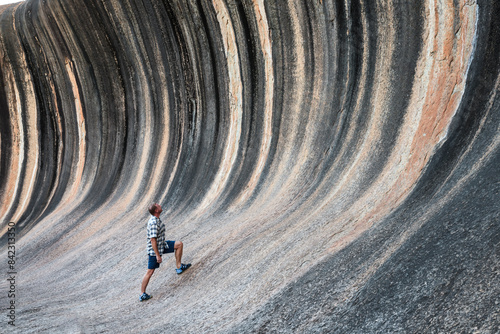 Man looking up at bizarre rock formation, Wave Rock, Western Australia