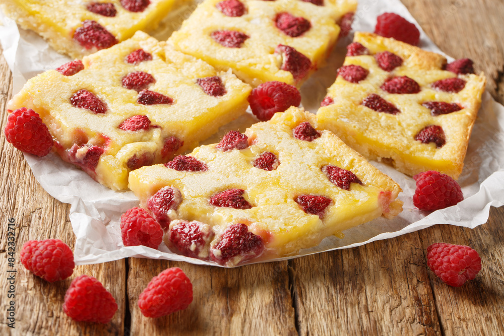 Delicious sweet dessert custard pie with fresh raspberries close-up on parchment on the table. Horizontal Delicious sweet dessert custard pie with fresh raspberries close-up on parchment on the table. Horizontal